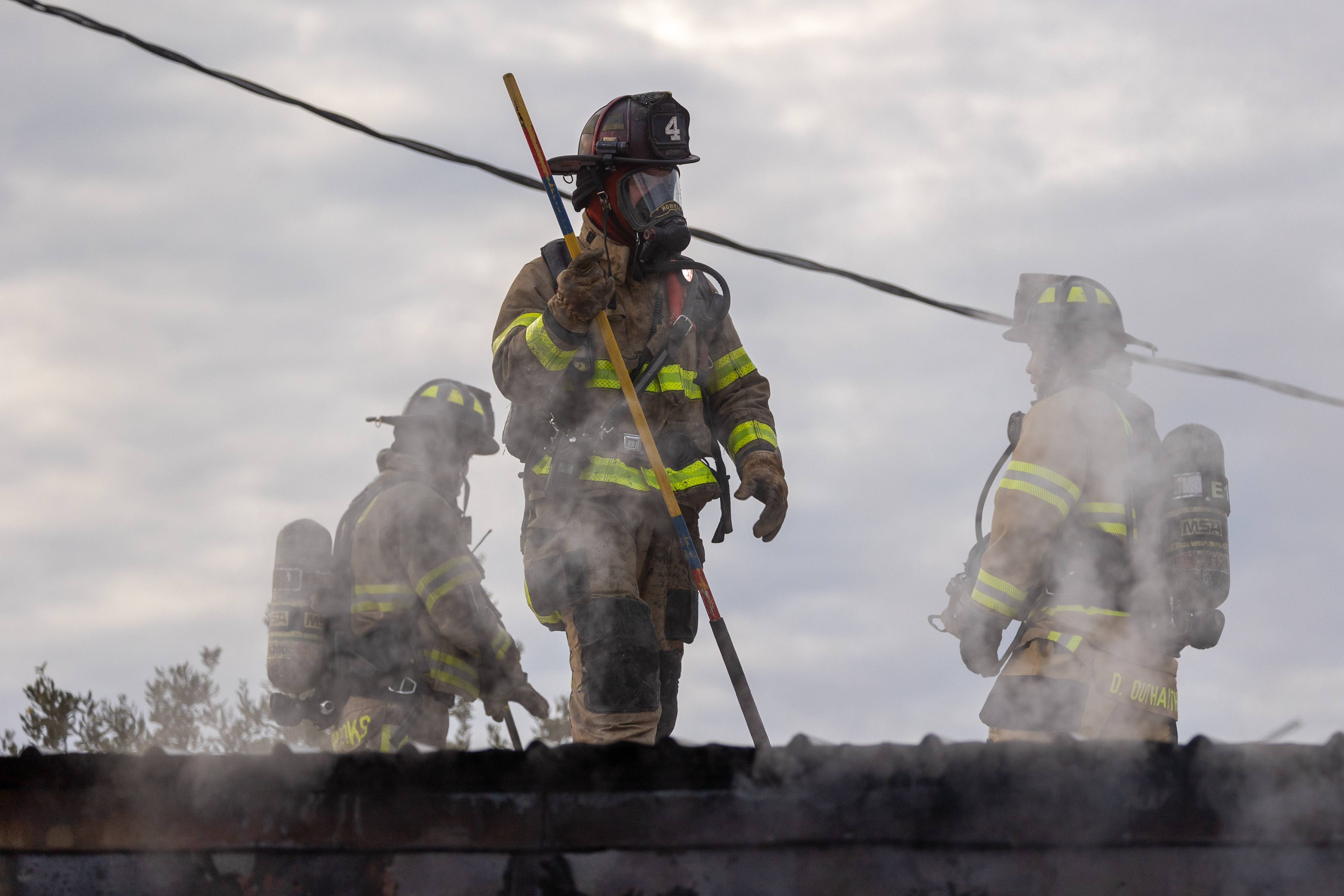 Firefighters work on roof of commercial building fire