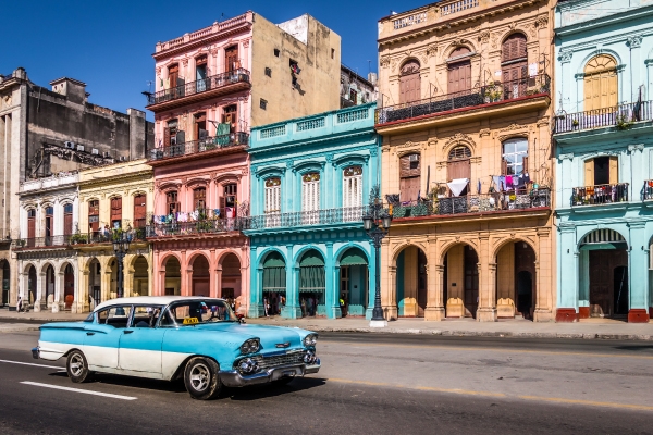 vintage blue car in front of colorful historic buildings